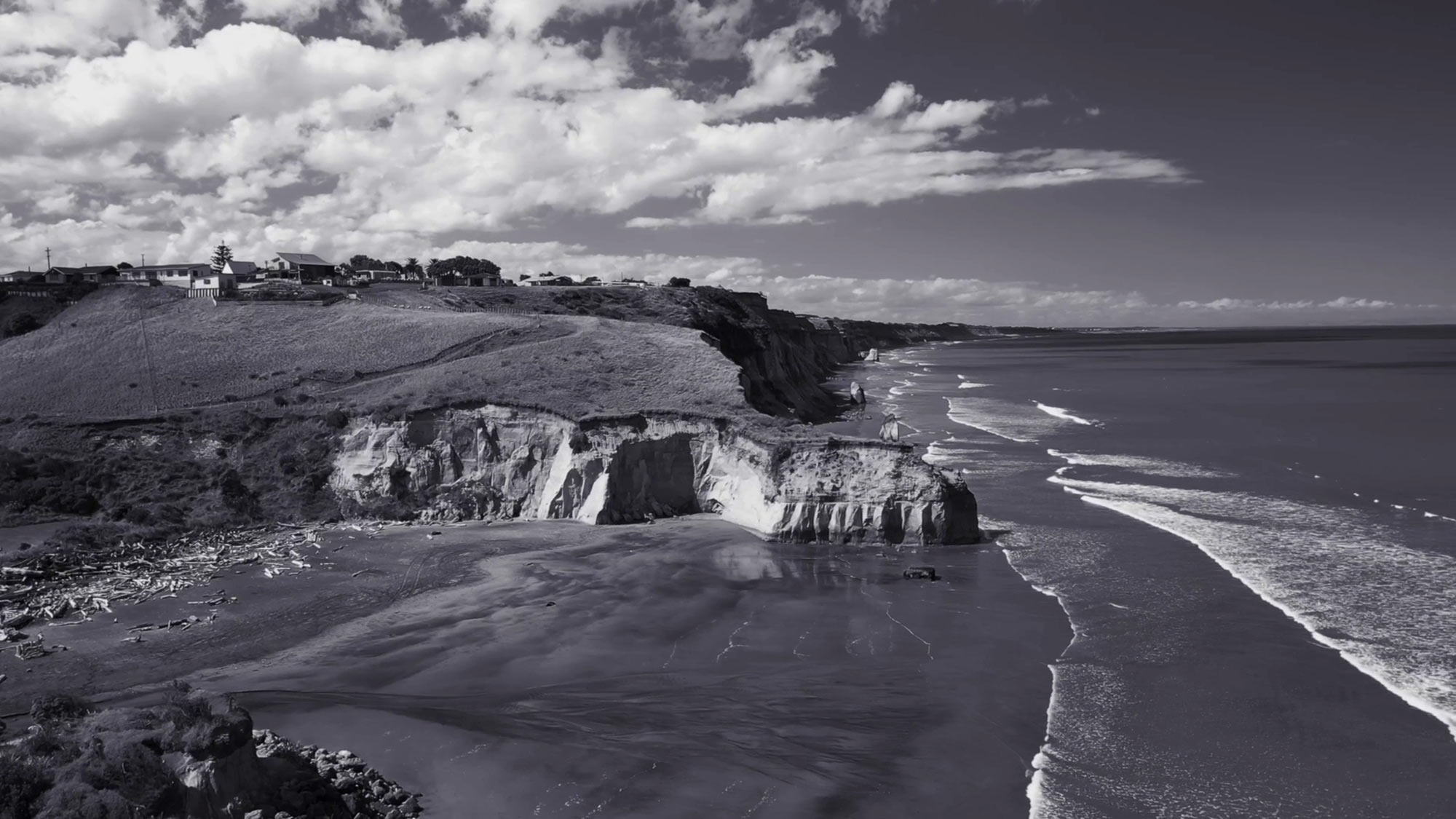 Black and white photo of Kai Iwi beach and the cliffs from above.