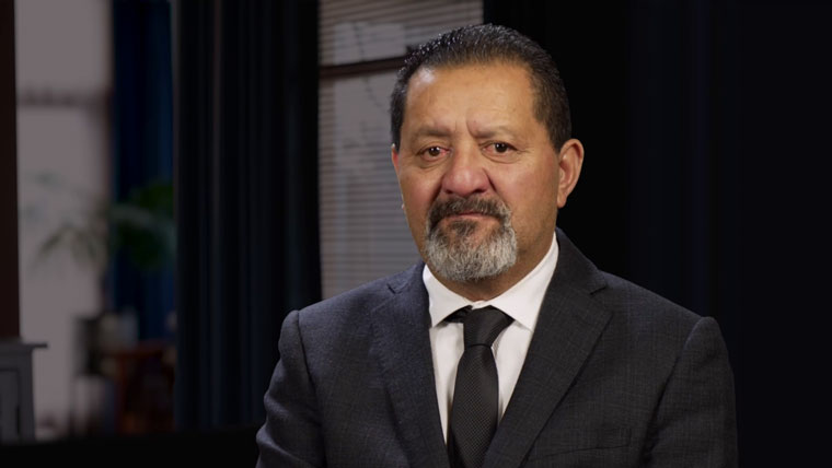 Mike Neho, he is wearing a black suit and tie.