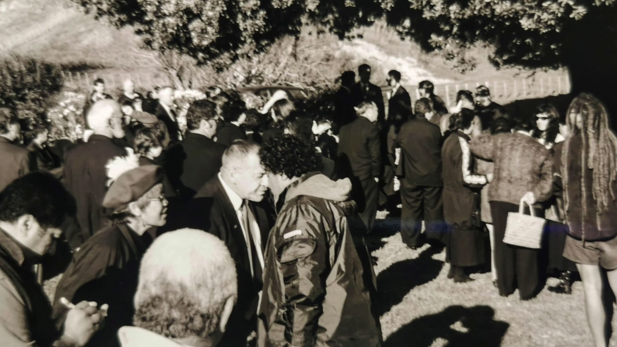Two people in the middle of a crowd having a hongi.