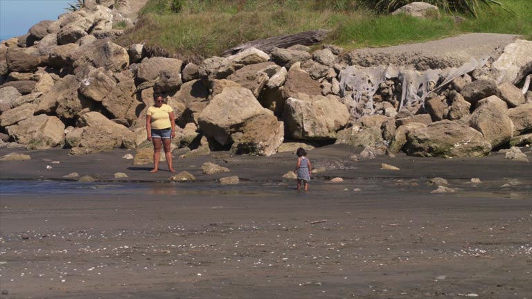 A mother and child near some rocks at Kai Iwi beach