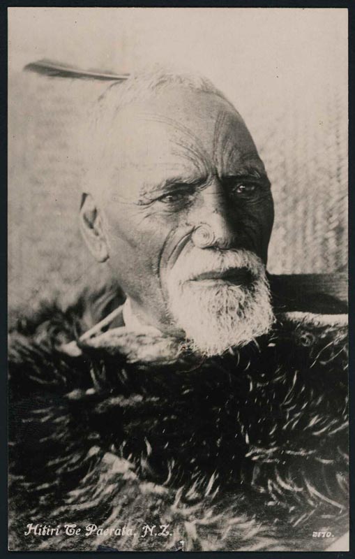 Grey-haired Māori man with tattooed face and feather in his hair. The words 'Hitiri Te Paerata, N.Z.' are written in the bottom left corner.