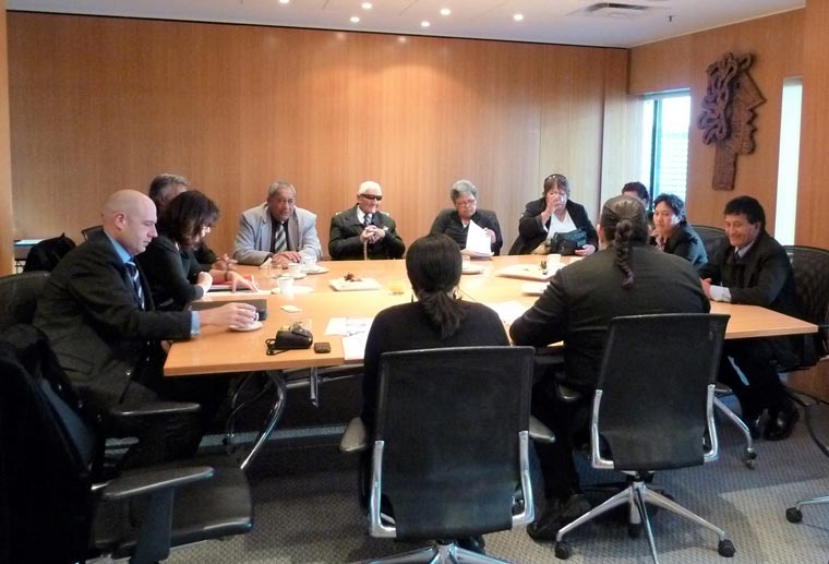 Men and women sitting around a square meeting table.