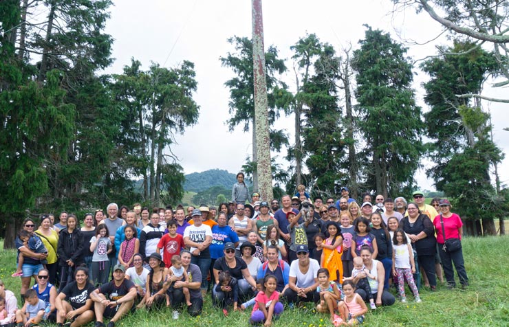 Group of adults and children posed in front of some trees